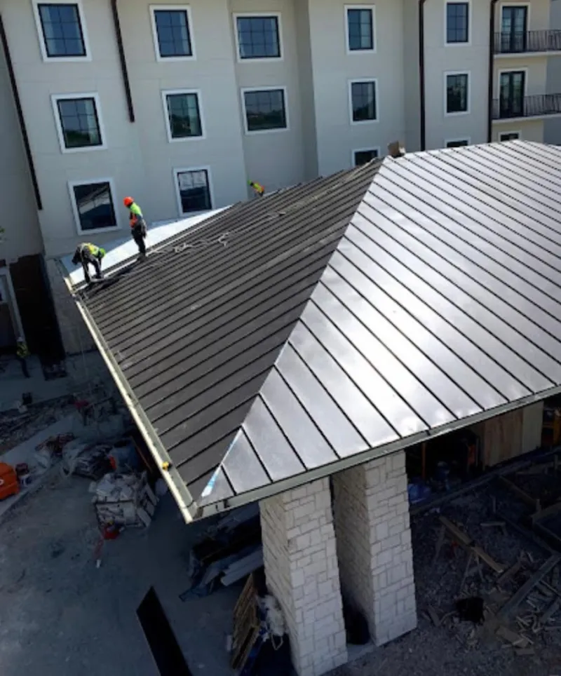 Crew installing standing seam metal roof panels on a commercial project in Waveland